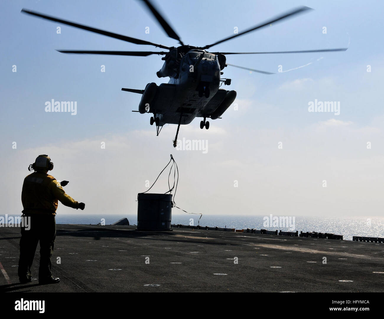 110423-N-ZS026-084 GULF OF ADEN (April 23, 2011) Aviation BoatswainÕs Mate 3rd Class Rodolfo Lopez signals a CH-53 Sea Stallion helicopter assigned to the Evil Eyes of Marine Medium Helicopter Squadron (HMM) 163 to detach cargo ropes after lowering an aircraft transmission container onto the flight deck of the amphibious assault ship USS Boxer (LHD 4). Boxer is underway supporting maritime security operations and theater security cooperation efforts in the U.S. 5th Fleet area of responsibility. (U.S. Navy photo by Mass Communication Specialist 3rd Class Trevor Welsh/Released) US Navy 110423-N- Stock Photo