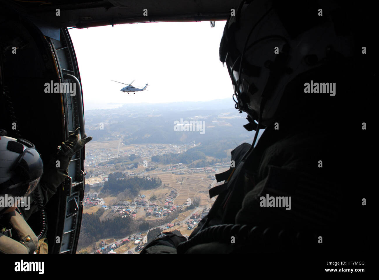 110313-N-SB672-010 TAKIHANA, Japan (March 13, 2011) Sailors assigned to the Black Knights of Helicopter Anti-Submarine Squadron (HS) 4, embarked aboard the aircraft carrier USS Ronald Reagan (CVN 76),  look out the starboard door as they prepare to deliver supplies during earthquake and tsunami relief efforts near Sendai, Japan. Ronald Reagan is off the coast of Japan rendering humanitarian assistance and disaster relief following an 8.9 magnitude earthquake and tsunami. (U.S. Navy photo by Mass Communication Specialist 3rd Class Dylan McCord/ Released) US Navy 110313-N-SB672-010 Sailors look  Stock Photo