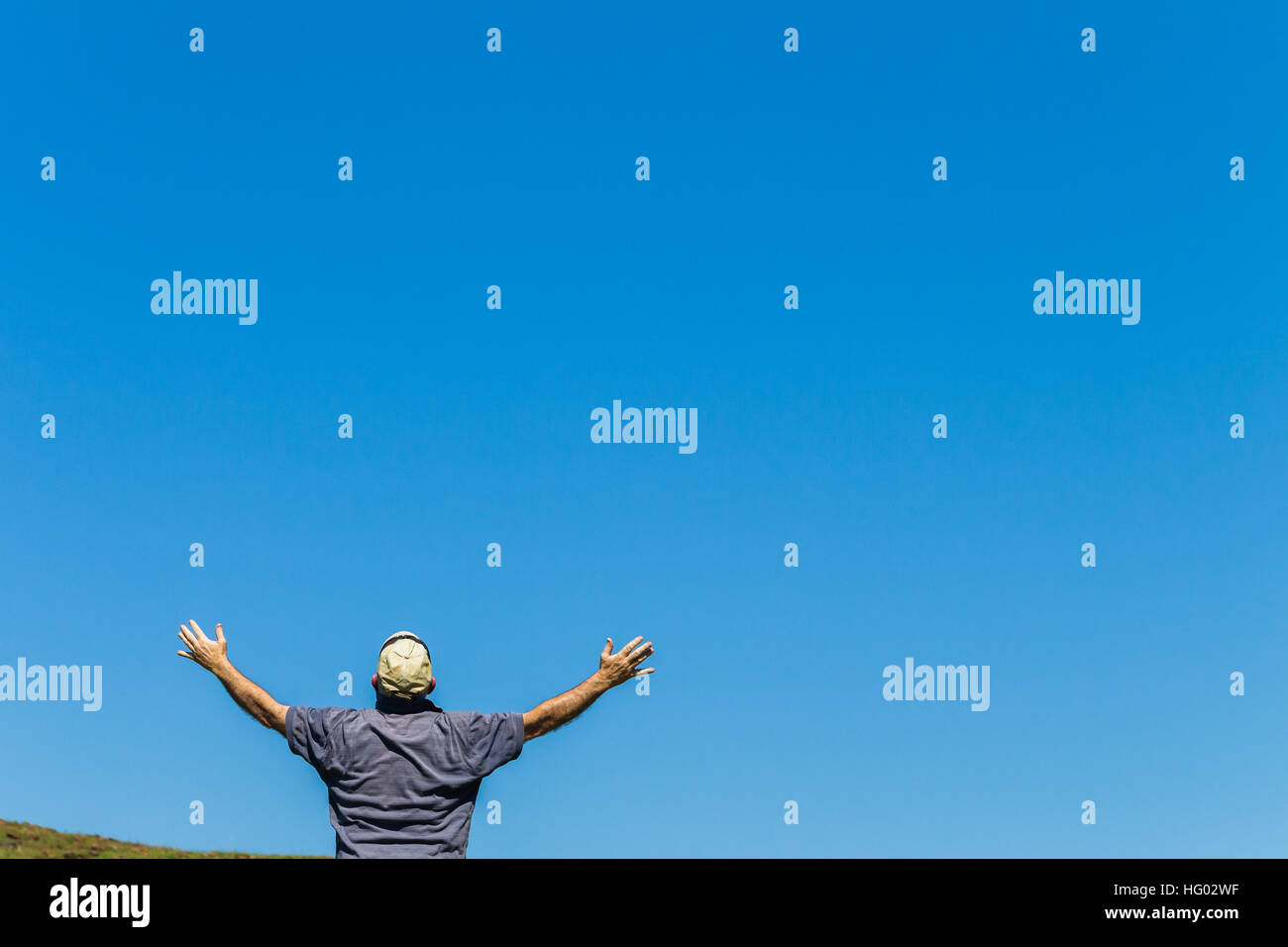 Man unidentified rear lifting hands into blue sky Stock Photo - Alamy