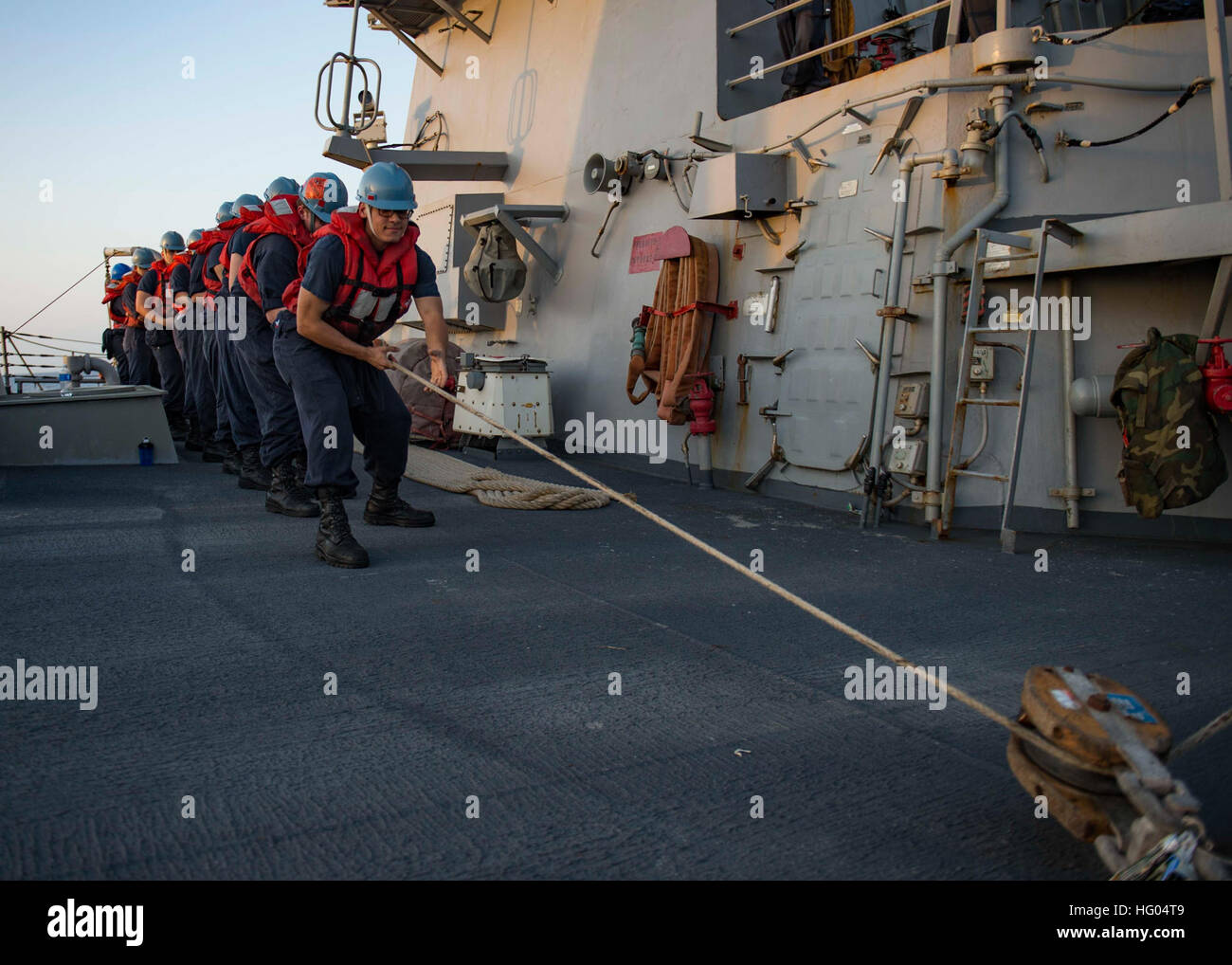 Sailors aboard guided-missile destroyer USS Stout (DDG 55) heave a line ...