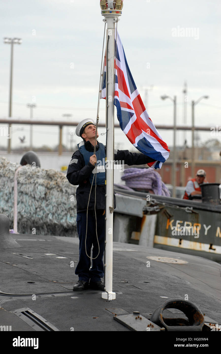 111128-N-NK458-092 NORFOLK (Nov. 28, 2011) A sailor assigned to the Royal Navy submarine HMS Astute (S119) prepares to raise the flag as the ship arrives at Naval Station Norfolk. Astute is the first in a new class of British nuclear submarines that sets the standard for the Royal Navy in terms of weapons load, communication facilities and stealth. Commissioned on Aug. 27, 2010, the 323-foot, 7,400-ton submarine carries a crew of 98 officers and enlisted personnel, and can travel at speeds of 29-plus knots while submerged. (U.S. Navy photo by Mass Communication Specialist 1st Class Todd A. Sch Stock Photo