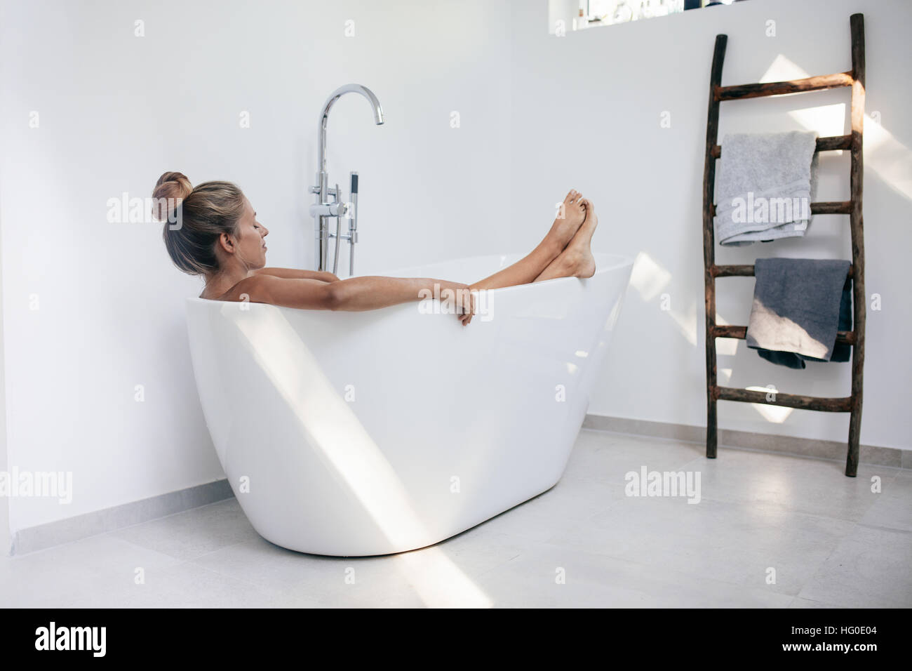Young woman relaxing in bathtub. Caucasian female lying in bathtub