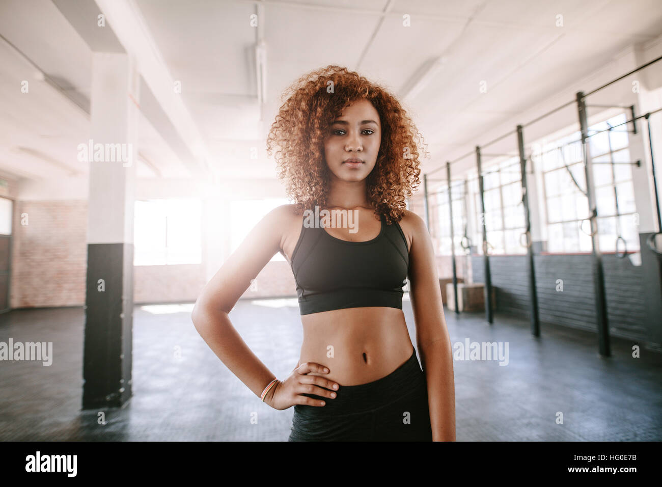 Portrait of determined african female standing in the gym. Beautiful black woman in sportswear in healthclub. Stock Photo