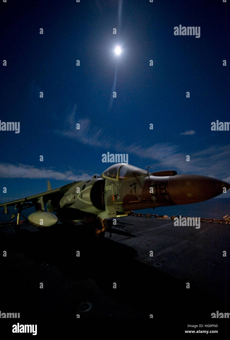 An AV-8B Harrier jet aircraft assigned to Marine Attack Squadron (VMA) 542 sits on the flight deck under a full moon aboard the forward-deployed amphibious assault ship USS Bonhomme Richard (LHD 6). Bonhomme Richard, commanded by Capt. Daniel Dusek, is the lead ship of the only forward-deployed amphibious ready group. (U.S. Navy photo by Mass Communication Specialist 2nd Class Michael Russell) USS Bonhomme Richard action 120830-N-KB563-336 Stock Photo