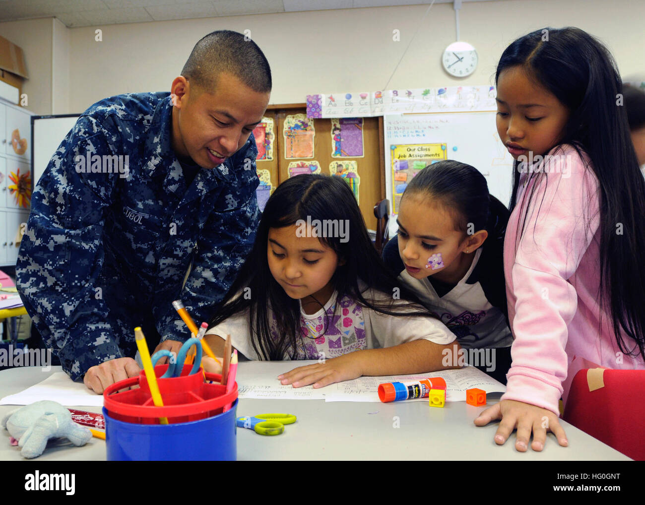 Culinary Specialist 1st Class Gomer Cubol, stationed aboard U.S. 7th Fleet flagship USS Blue Ridge (LCC 19), helps second grade students at Yokosuka Naval Base's Sullivans Elementary School with a classroom assignment during a community service event Feb. 14. (U.S. Navy photo by Mass Communications Specialst 2nd Class Jeff Troutman) USS Blue Ridge community service event 130214-N-ON468-078 Stock Photo