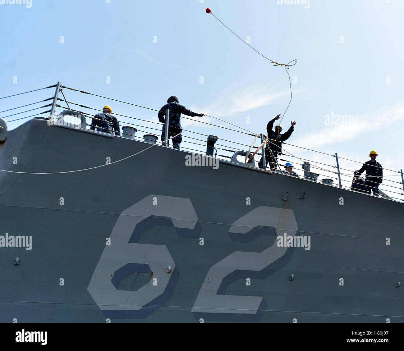 A USS Fitzgerald (DDG 62) sailor tosses a heaving line toward the pier ...