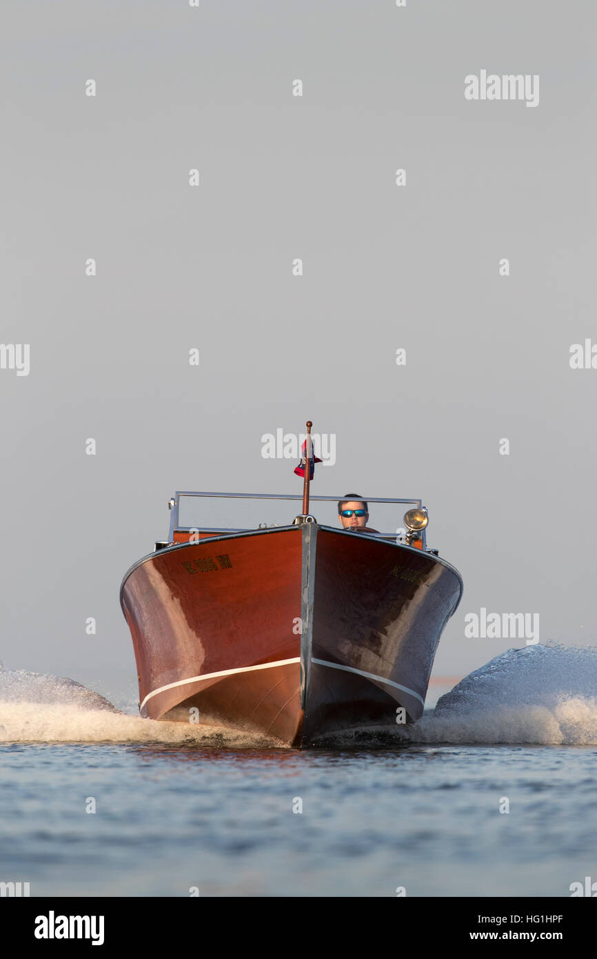 A fast approaching wooden speedboat with a man driving. Stock Photo