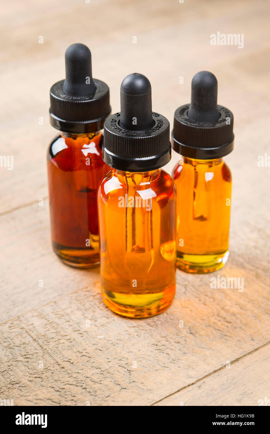 Vaping ecig juice bottles over wood background. EJuice in bottle with