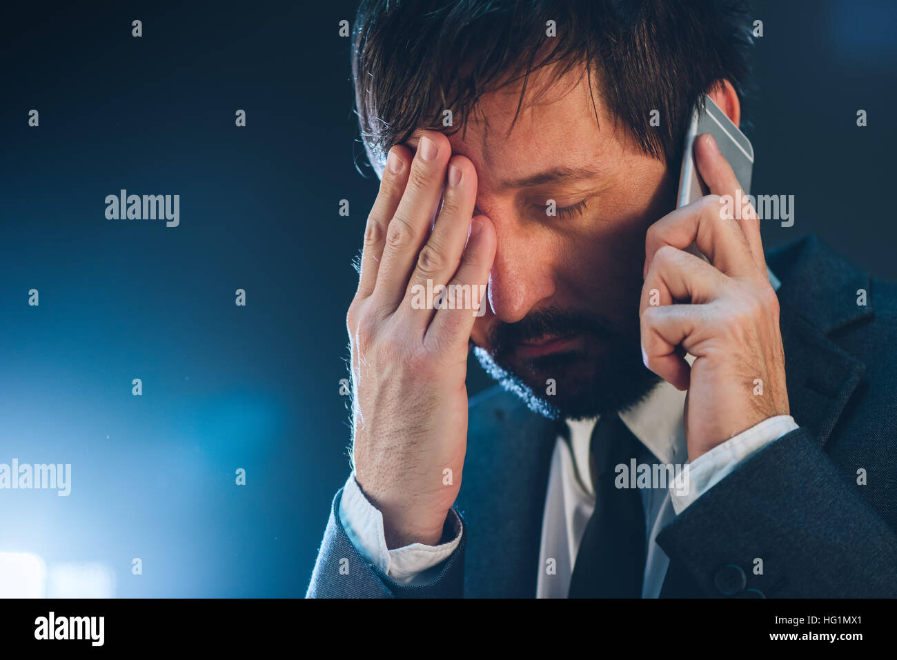 Late night business phone call with mobile, tired and exhausted businessman having conversation with his superior Stock Photo