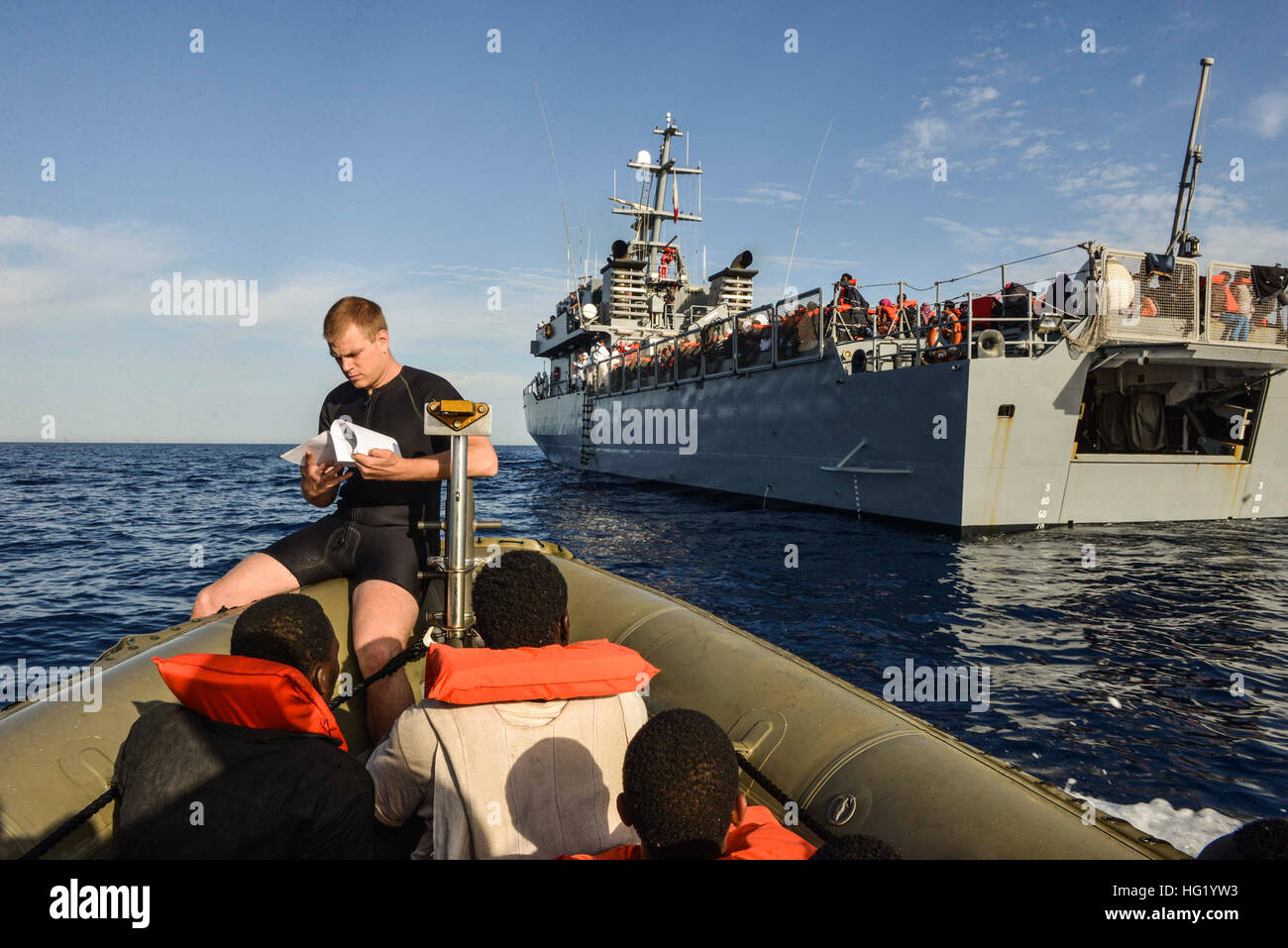 U.S. Navy Boatswain's Mate 2nd Class Cory Esworthy, top left, a search and rescue swimmer, assists with transporting persons in distress on a rigid-hull inflatable boat to Armed Forces of Malta offshore patrol vessel P61 June 7, 2014, in the Mediterranean Sea. The Bataan and the guided missile frigate USS Elrod (FFG 55) rendered assistance and provided food, water, medical attention and temporary shelter to 282 people after receiving a report that an Italian military marine patrol aircraft sighted six small vessels, one of which was sinking. The Bataan, with elements of the 22nd Marine Expedit Stock Photo