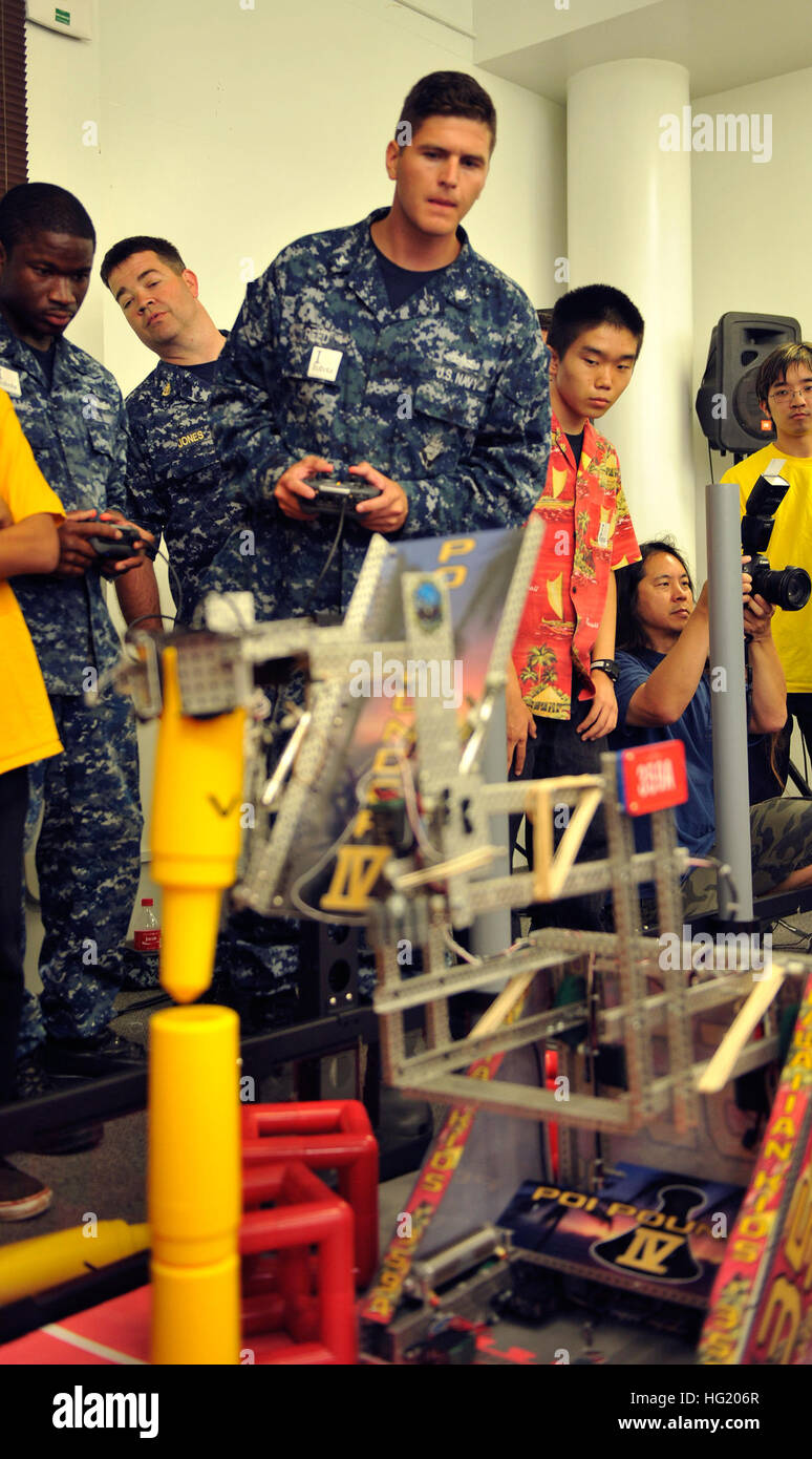 Electronics Technician 3rd Class Joel Reed from the USS Cape St. George (CG 71) pilots a robot during a high school robotics competition held at Pearl Harbor Naval Shipyard. The robot, built by Yoshio Yoshizumi of Waialua High School, was one of several entries in the Rim of the Pacific (RIMPAC) Exercise 2014 Robotics Competition, sponsored by the U.S. Pacific Fleet and the Office of Naval Research. While showing off their entries, students had a chance to meet RIMPAC participants and build proficiency in Science, Technology, Engineering, and Math (STEM) skills. Twenty-two nations, more than 4 Stock Photo