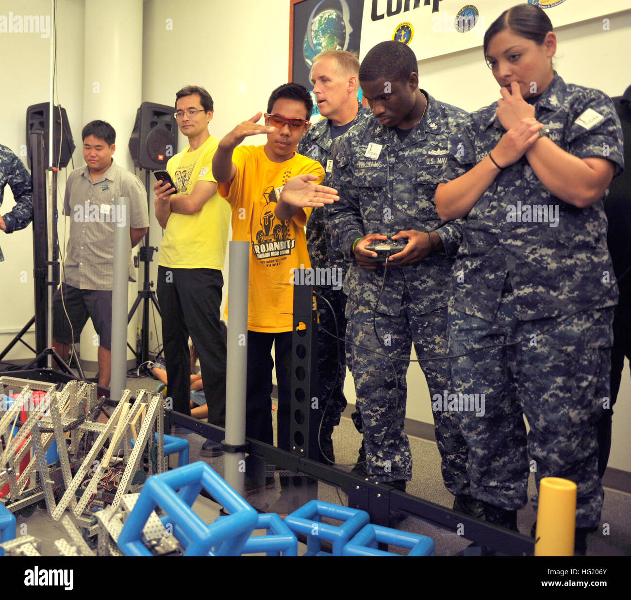 Noah Evile, a sophomore at Mililani High School, instructs Operations Specialist 2nd Class Jerome Williams and Gunner's Mate 1st Class Jennifer Dickson from USS Cape St. George (CG 71) in piloting the Mililani team's robot during a robotics competition that included Sailors piloting robots designed and built by students. The competition, sponsored by the U.S. Pacific Fleet and the Office of Naval Research, gave the students a chance to meet Rim of the Pacific (RIMPAC) Exercise 2014 participants and learn about the Navy while building proficiency in Science, Technology, Engineering, and Math (S Stock Photo