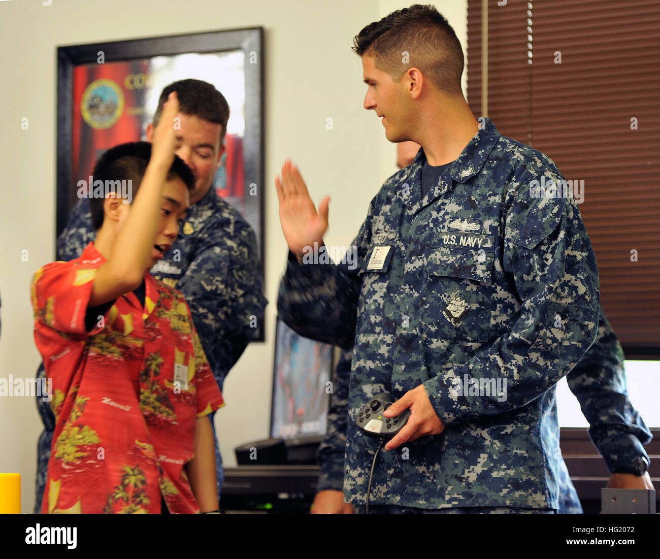 Yoshio Yoshizumi, a Waialua High School senior, and Electronics Technician 3rd Class Joel Reed from the USS Cape St. George (CG 71) high-five after a robotics competition which included Sailors piloting robots built by the students. The competition, sponsored by the U.S. Pacific Fleet and the Office of Naval Research, gives the students a chance to learn about the Navy and builds proficiency in Science, Technology, Engineering, and Math (STEM) skills. The world's largest international maritime exercise, Rim of the Pacific (RIMPAC) Exercise 2014 provides a unique training opportunity that helps Stock Photo