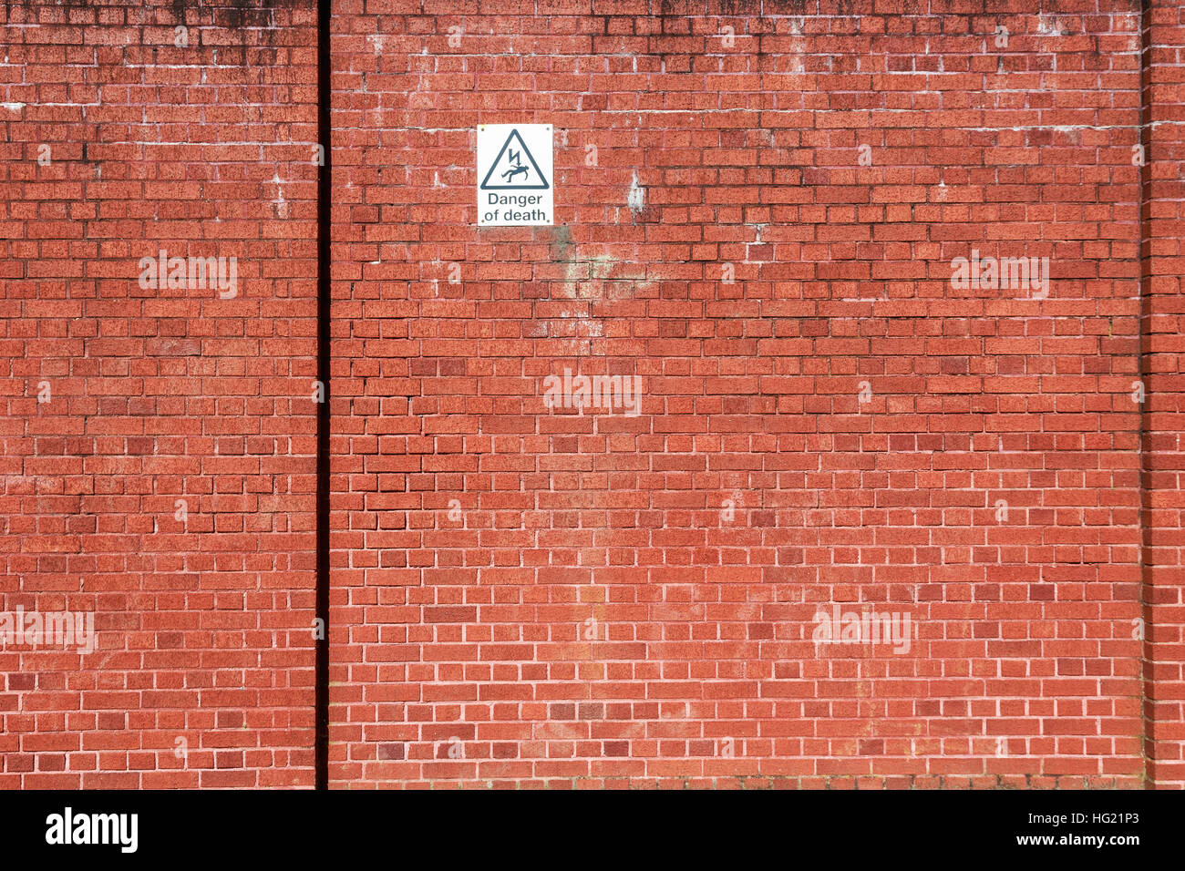 Red brick wall with a warning sign of high voltage danger Stock Photo