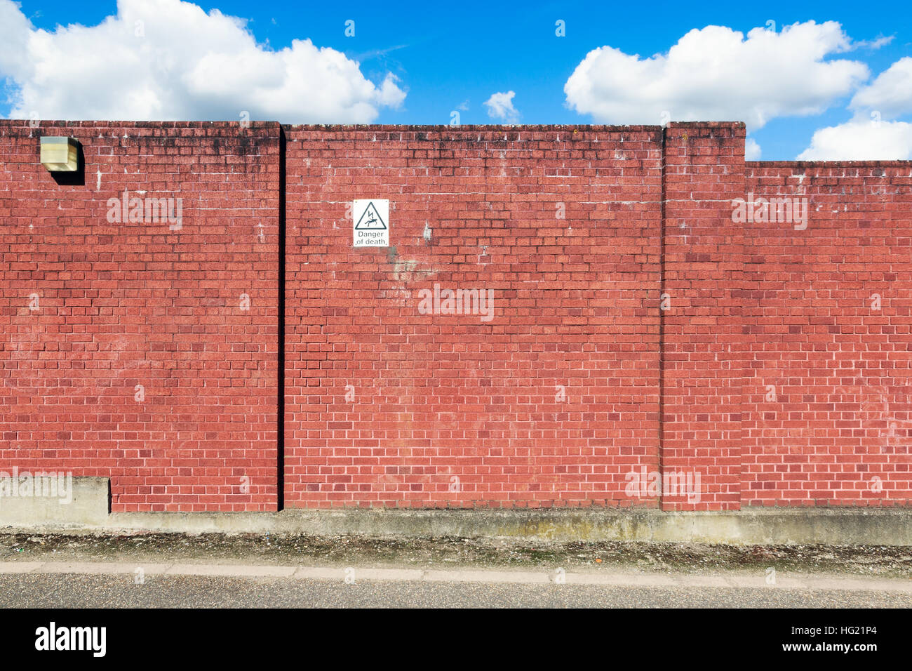 Red brick wall with a warning sign of high voltage danger Stock Photo