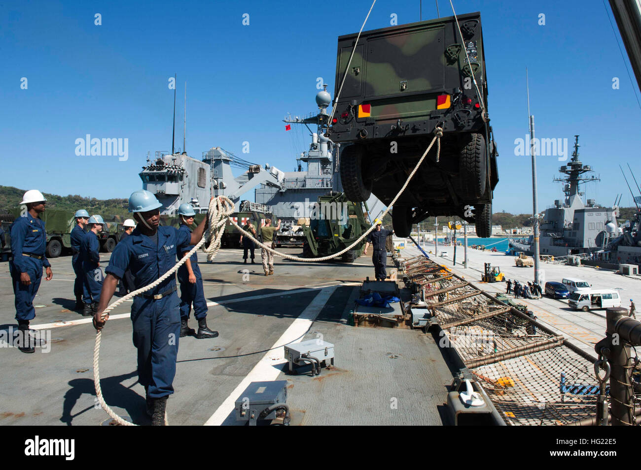 Sailors man tending lines as a crane hoists a Humvee, assigned to the 31st Marine Expeditionary Unit (MEU), off the flight deck of the amphibious dock landing ship USS Germantown (LSD 42) during an equipment offload in White Beach, Okinawa. Germantown is part of the Peleliu Amphibious Ready Group, commanded by Capt. Heidi Agle, and is conducting joint forces exercises in the U.S. 7th Fleet area of responsibility.  (U.S. Navy Photo by Mass Communication Specialist 2nd Class Amanda R. Gray/Released) USS Germantown 141021-N-UD469-134 Stock Photo