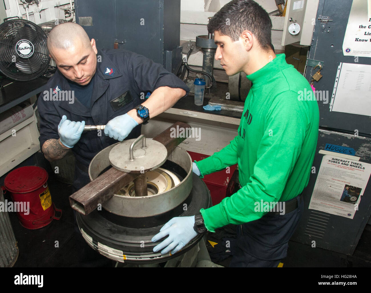 150703-N-YD641-061 PHILIPPINE SEA (July 3, 2015) Aviation Structural Mechanic 2nd Class Ivan Ramirez, from San Diego, left, and Aviation Structural Mechanic Airman Sergio Castan assembles a nose mount tire in the wheel and tire shop aboard the Nimitz-class aircraft carrier USS George Washington (CVN 73). George Washington and its embarked air wing, Carrier Air Wing (CVW) 5, are on patrol in the 7th Fleet area of responsibility supporting security and stability in the Indo-Asia-Pacific region. George Washington will conduct a hull-swap with the Nimitz-class aircraft carrier USS Ronald Reagan (C Stock Photo