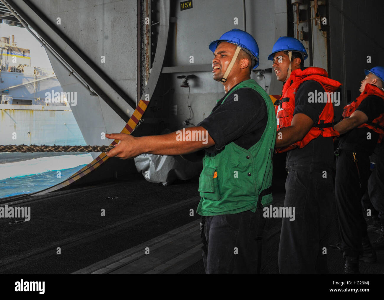 150909-N-CQ428-078  ARABIAN GULF (September 09, 2015) – Sailors handle line in the hangar bay aboard the aircraft carrier USS Theodore Roosevelt (CVN 71) during a replenishment-at-sea with the Military Sealift Command fast combat support ship USNS Arctic (T-AOE 8). Theodore Roosevelt is deployed in the U.S. 5th Fleet area of operations supporting Operation Inherent Resolve, strike operations in Iraq and Syria as directed, maritime security operations and theater security cooperation efforts in the region. (U.S. Navy photo by Mass Communication Specialist 3rd Class Jennifer Case/Released) USS T Stock Photo