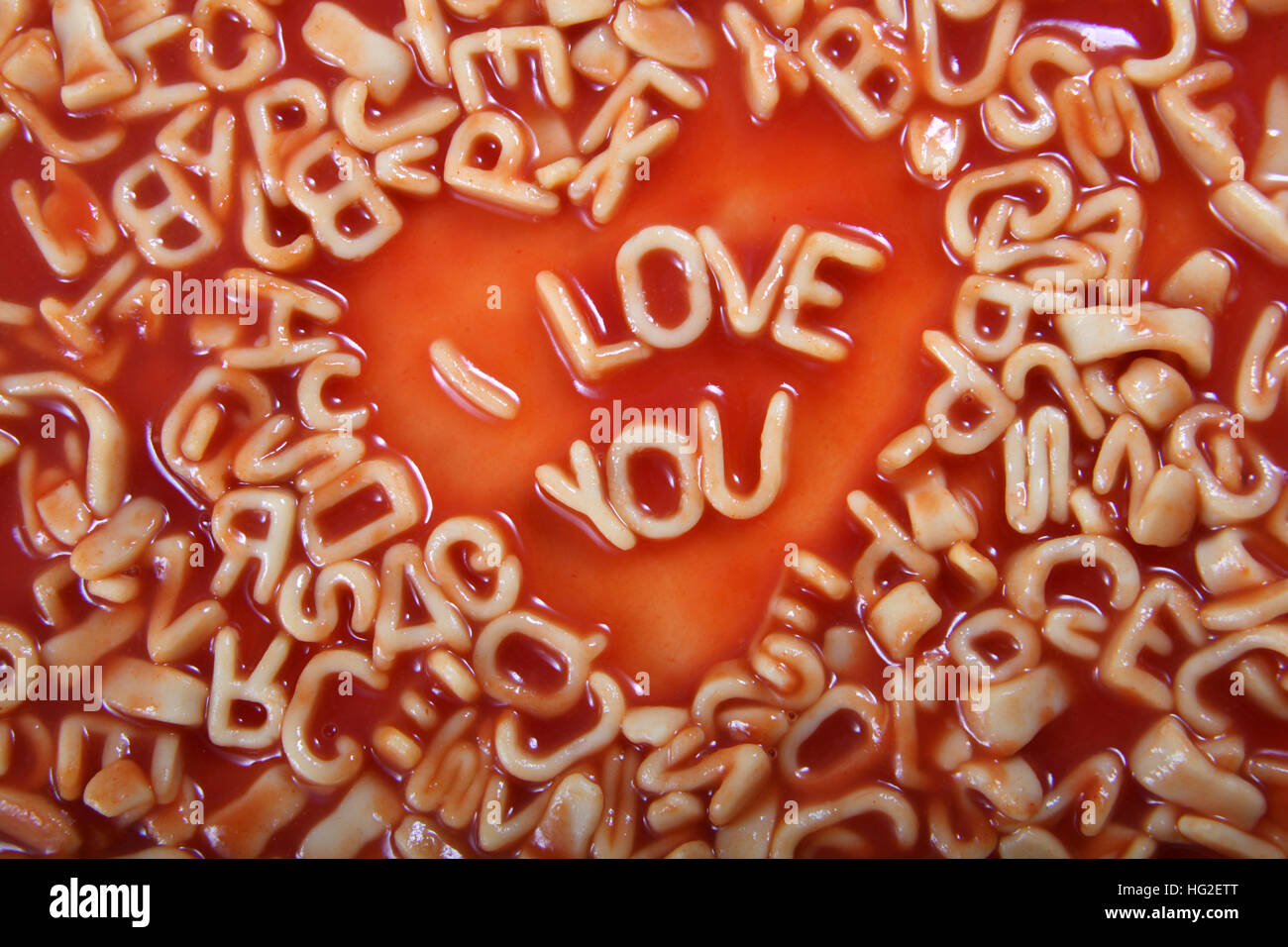 i Love you text written in Alphabetti Spaghetti pasta shaped letters, with tomato sauce around it. Stock Photo