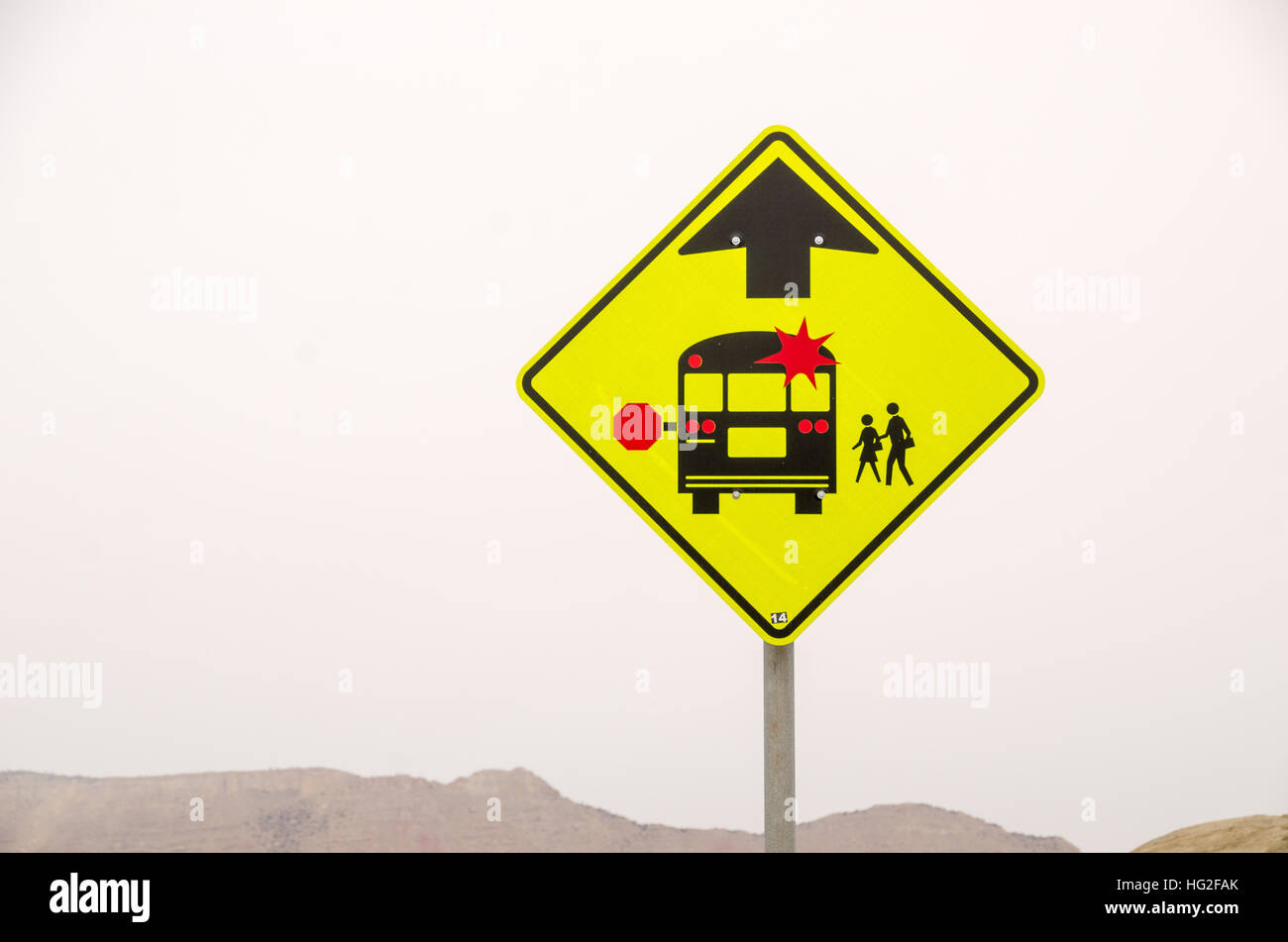 Brightly colored sign to warn of a school bus stop ahead Stock Photo