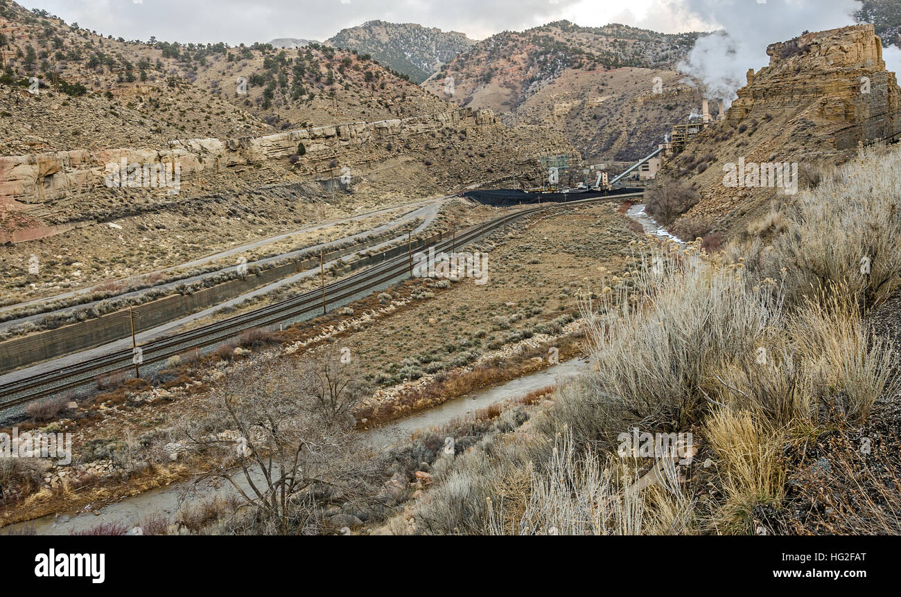Railroad tracks lead your eye to the steam from a coal-burning power plant in Utah Stock Photo