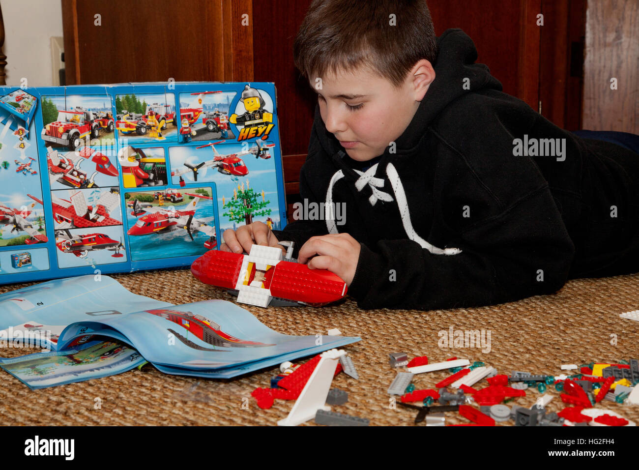 Boy age 10 building a Lego airplane with instruction book open for study and guidance. St Paul Minnesota MN USA Stock Photo