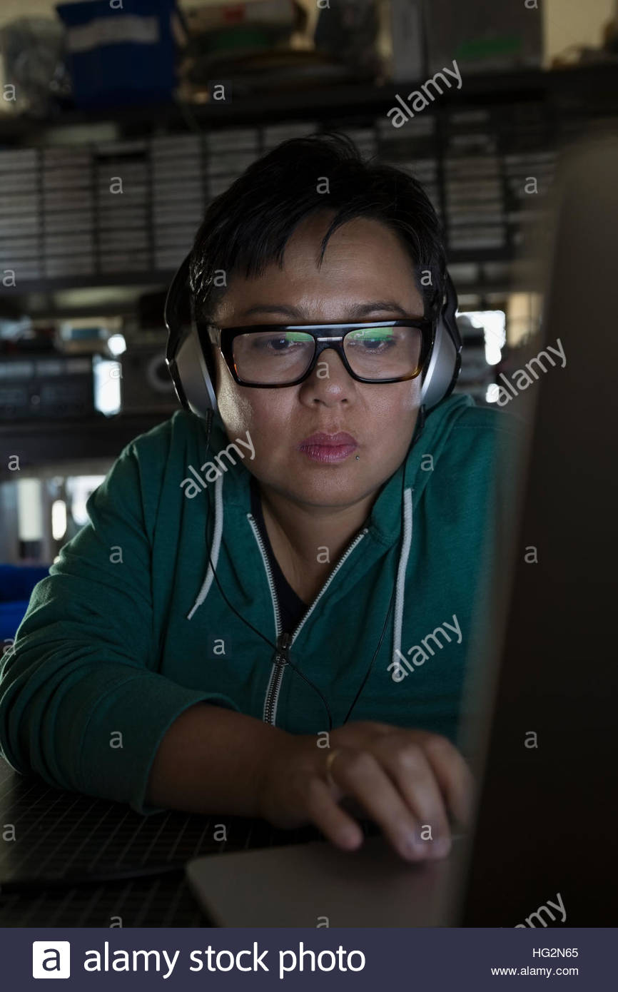 Close up serious female computer programmer working at laptop wearing ...