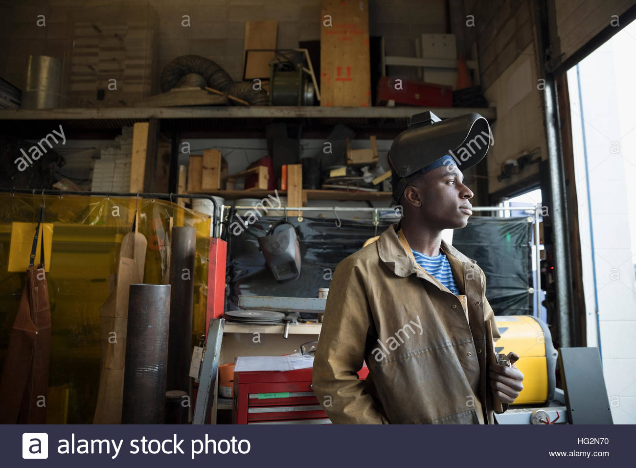 Pensive welder wearing protective workwear looking away in workshop Stock Photo