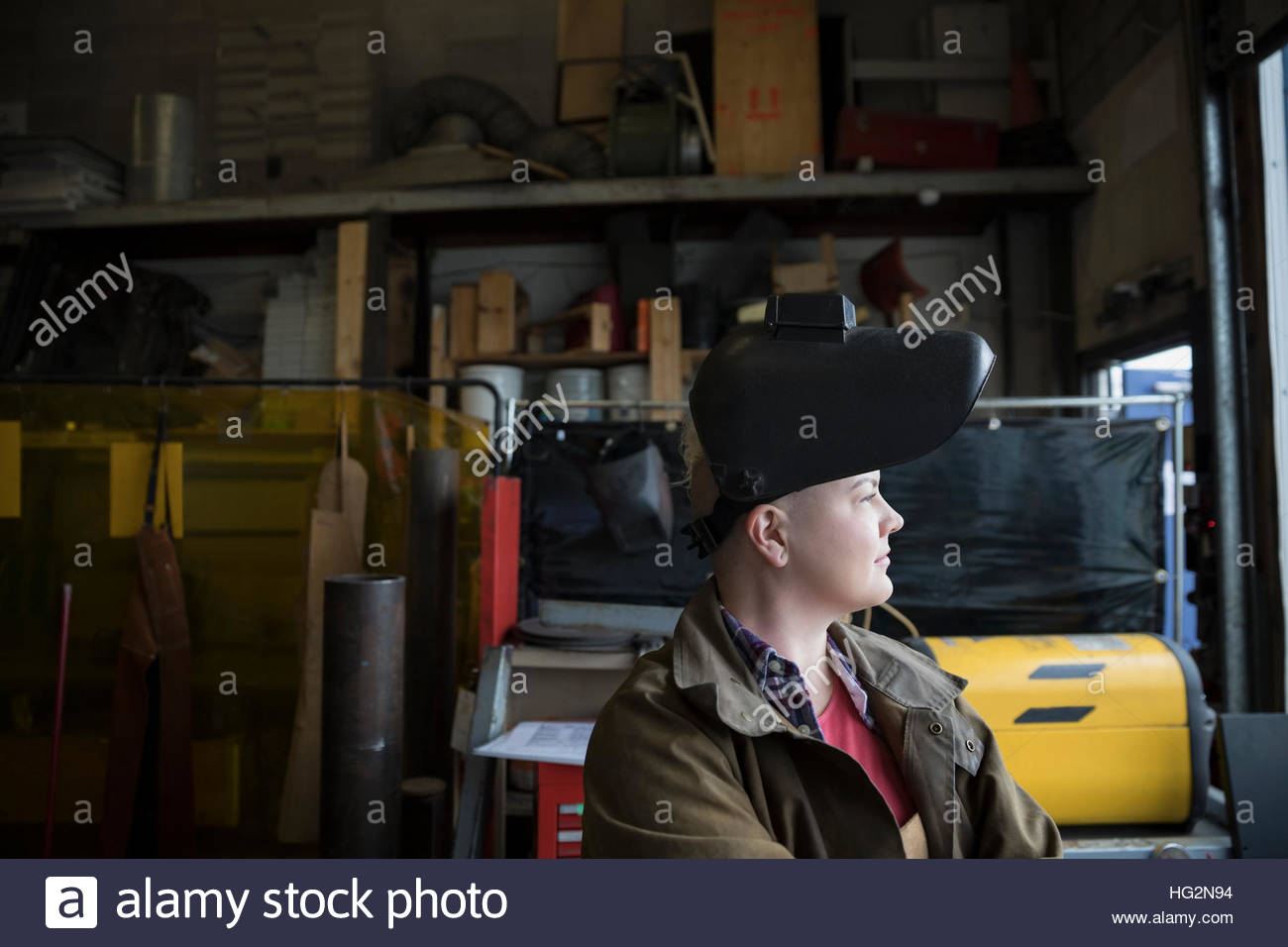Pensive female welder wearing protective workwear looking away Stock Photo