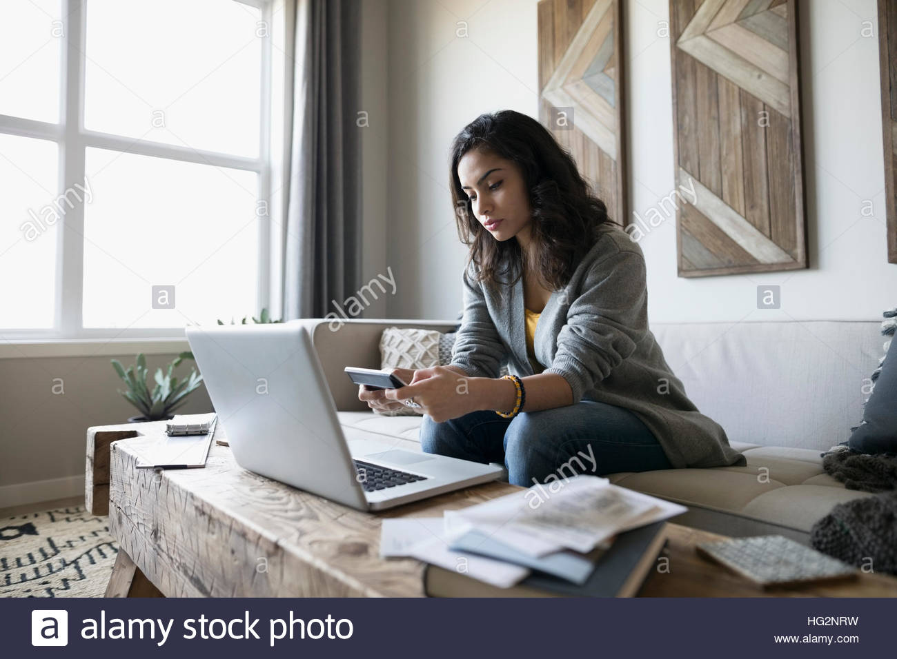 Young woman with laptop and calculator paying bills online on living room sofa Stock Photo Alamy