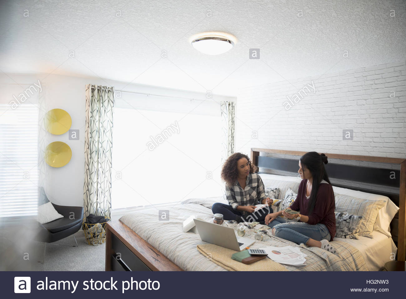 Mother with laptop teaching daughter personal finance management in bedroom Stock Photo