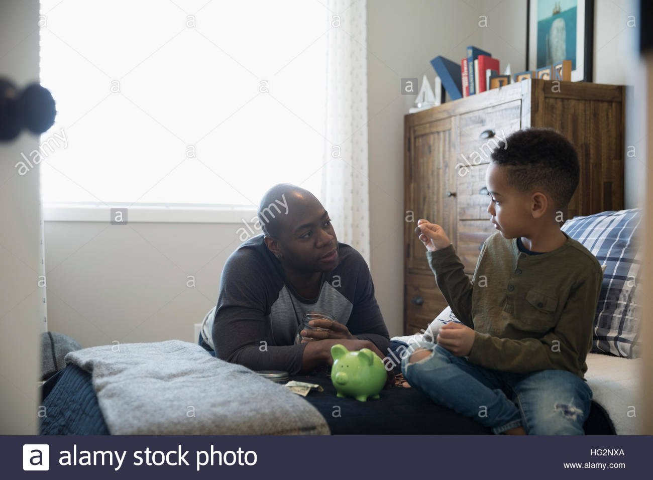 Father and son depositing coins into piggy bank in bedroom Stock Photo ...