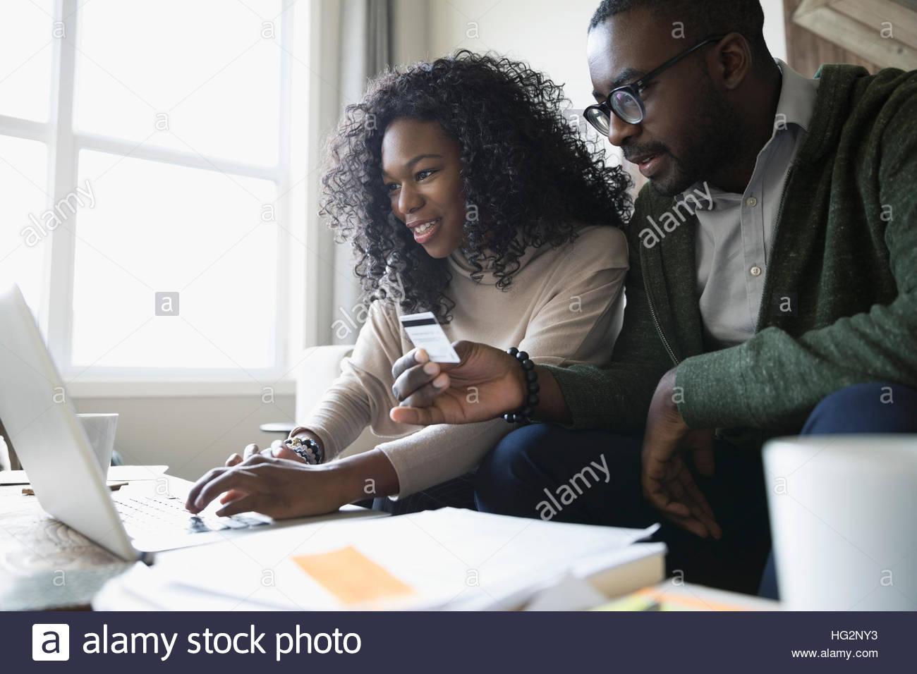 Couple with credit card and laptop paying bills online in living room Stock Photo