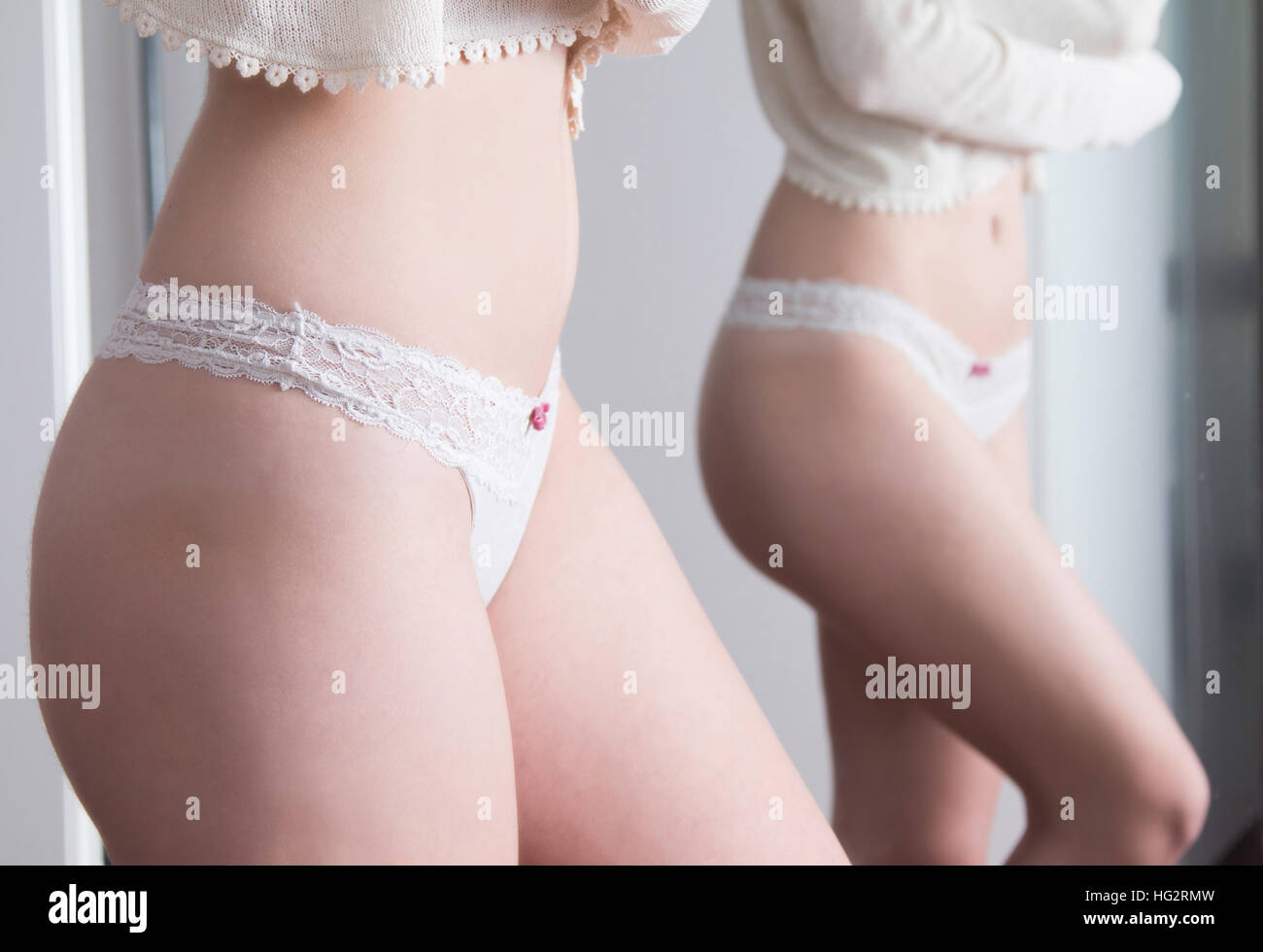 Sexy girl in white panties standing next to mirror, body detail