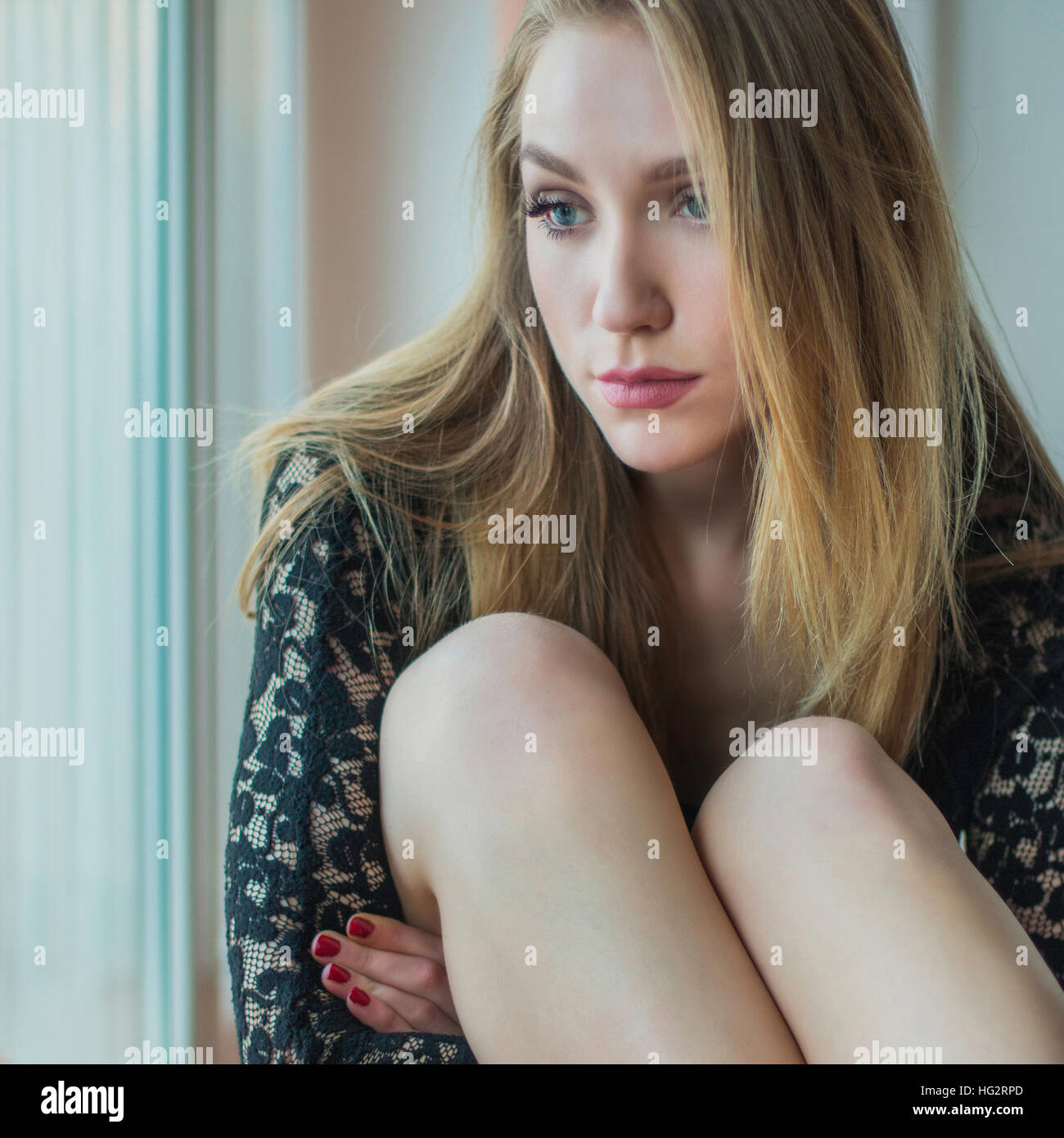Young sexy blonde girl in panties and sweater standing next to window,  looking emotive and thoughtful Stock Photo - Alamy