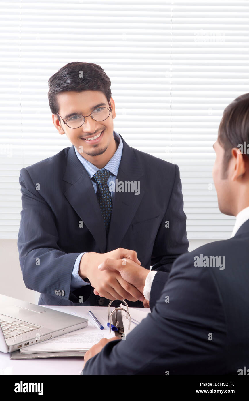 Two young professional men shaking hands with smile in office cabin Stock Photo