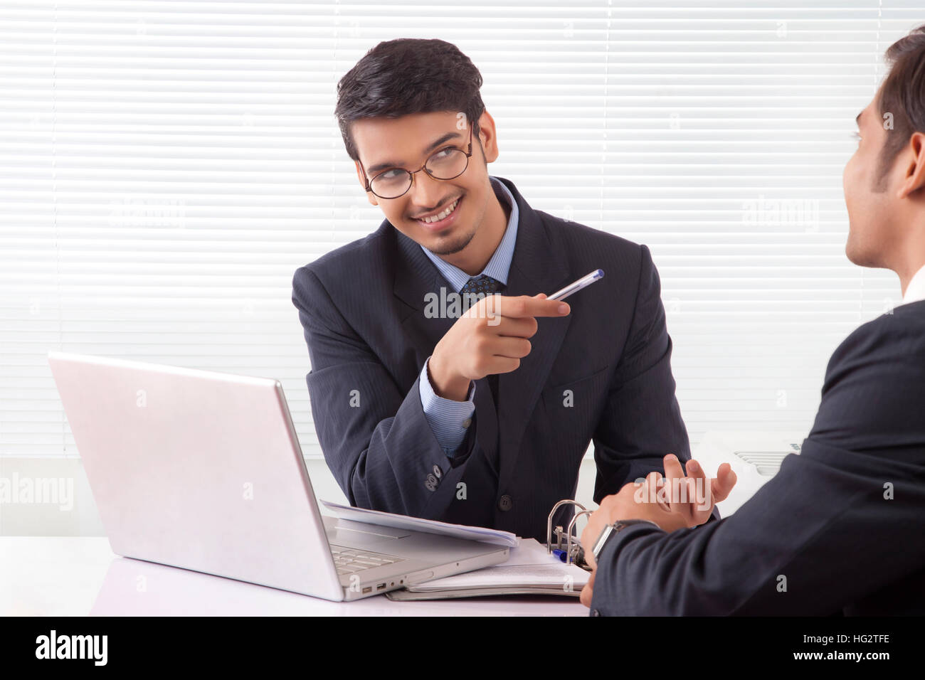 Two young professional men in happy mood while discussing work at office Stock Photo
