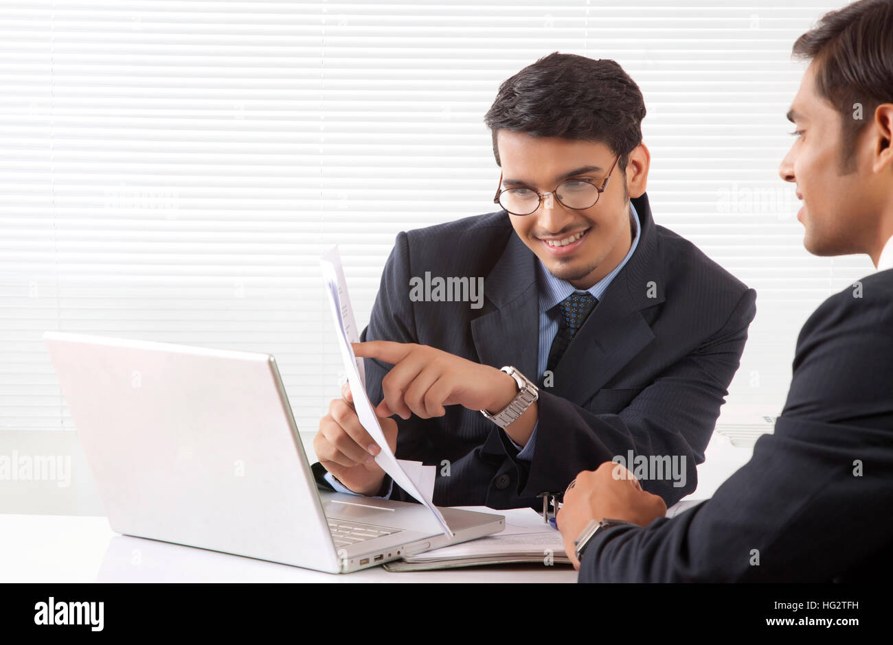 Two young professional men discussing work looking at document inside office cabin Stock Photo