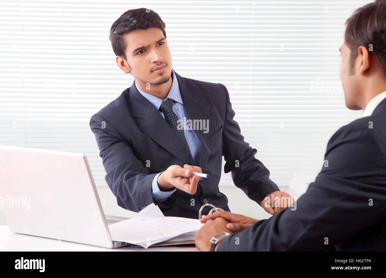 Two businessmen seriously discussing work at office Stock Photo