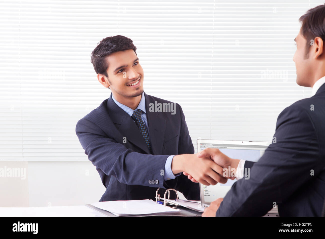 Two business men shaking hands with smile in office cabin Stock Photo