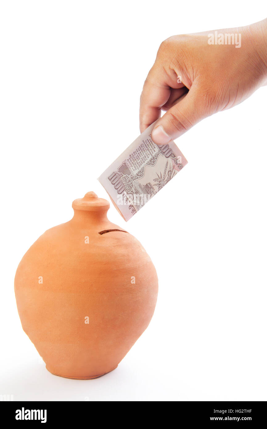 Man putting indian currency into money bank Stock Photo