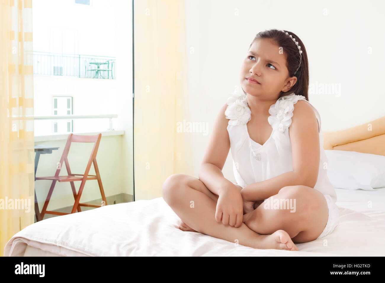 Pensive girl sitting on bed Stock Photo