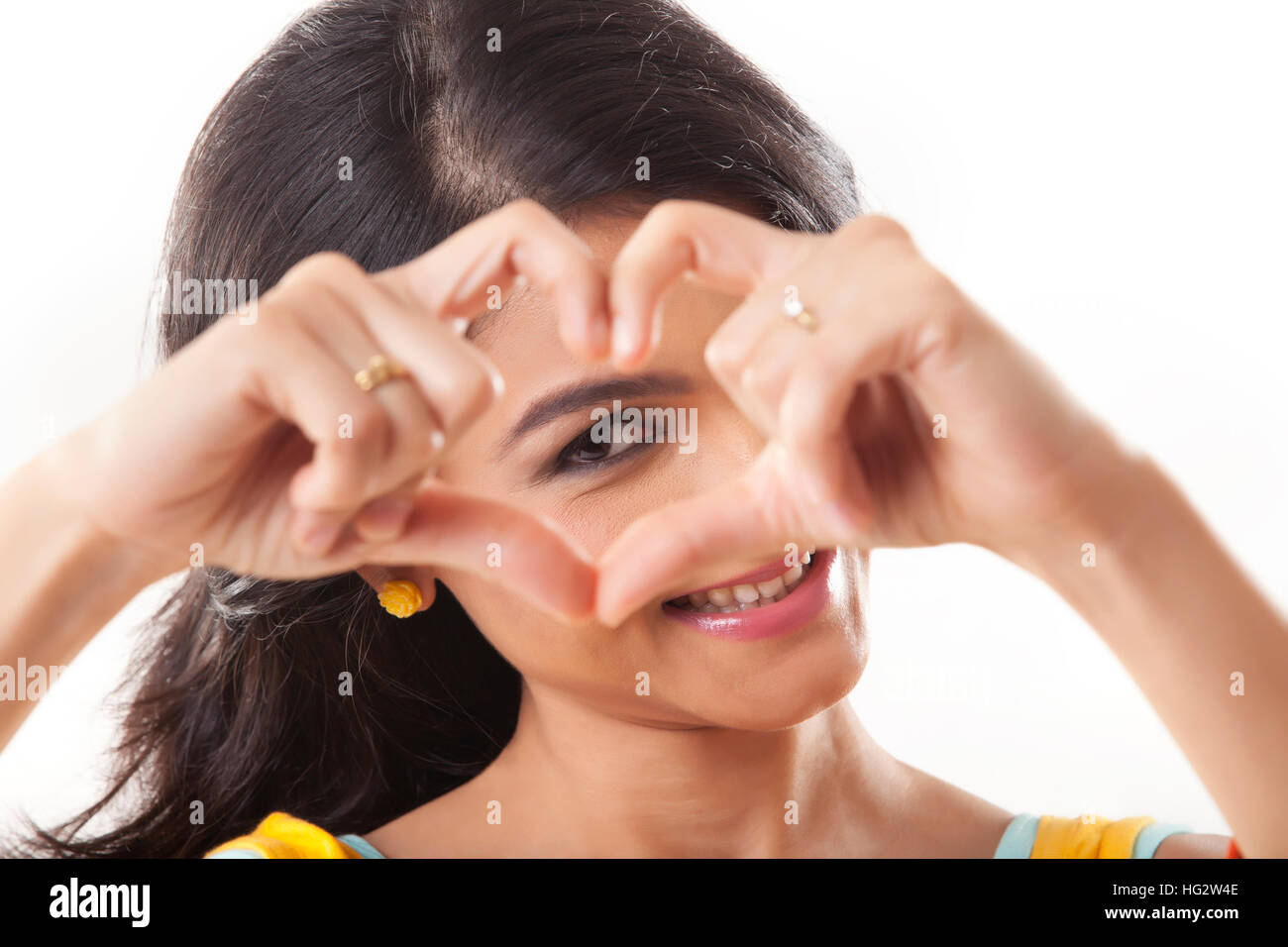 Cute young female making a heart sign isolated on white Stock Photo
