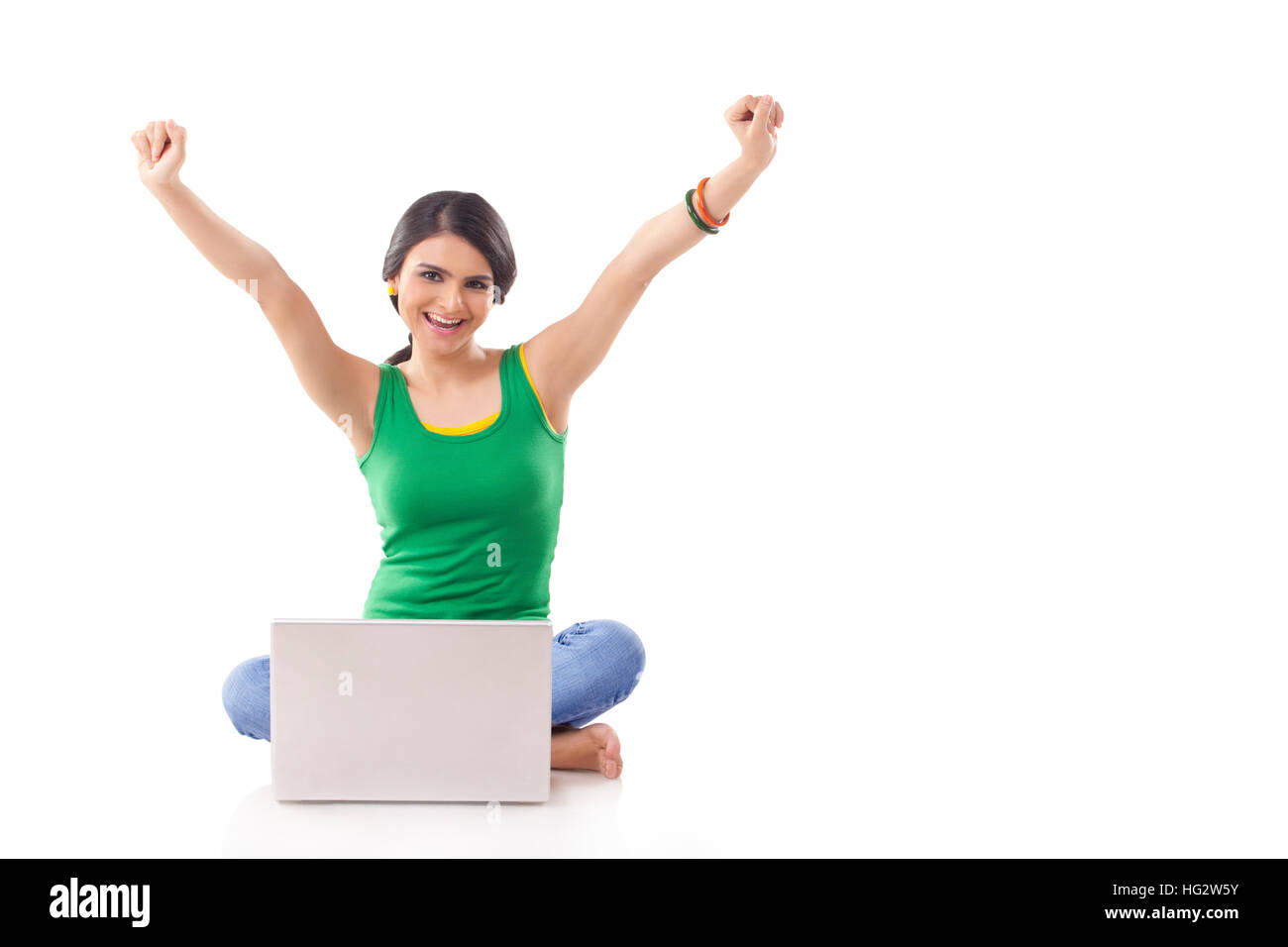 young woman cheering at camera with laptop sitting on floor Stock Photo