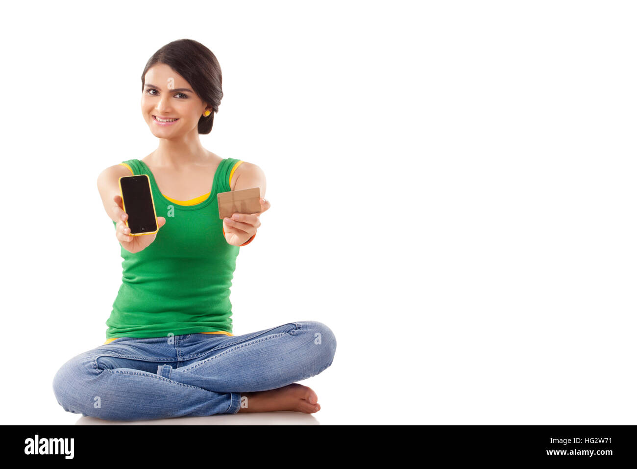 Portrait of a young woman  sitting on floor and holding a mobile phone and a credit card Stock Photo