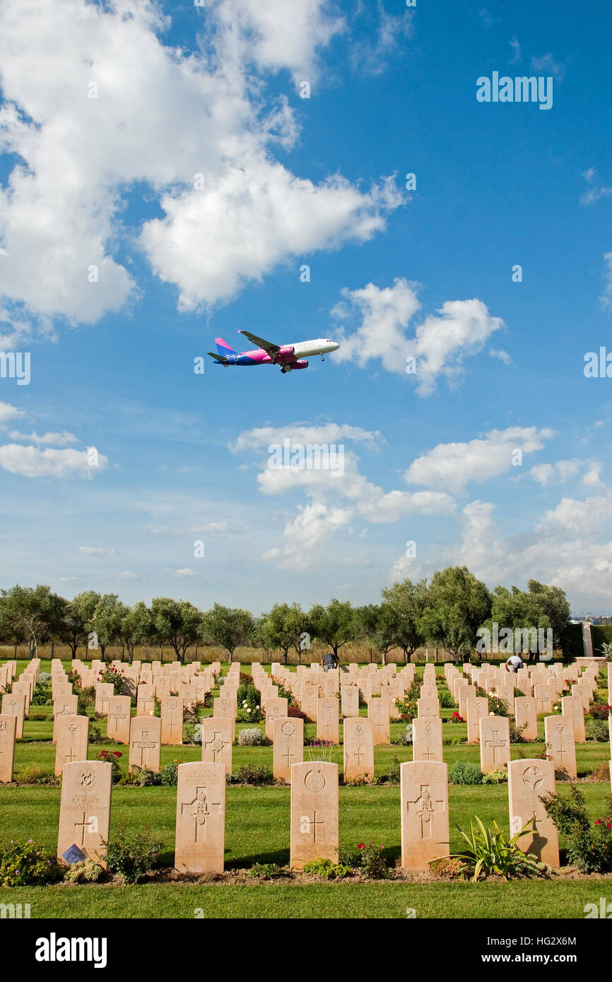 Airliner on finals to land at Catania Airport, Sicily, passes over Catania CWGC Cemetery Stock Photo