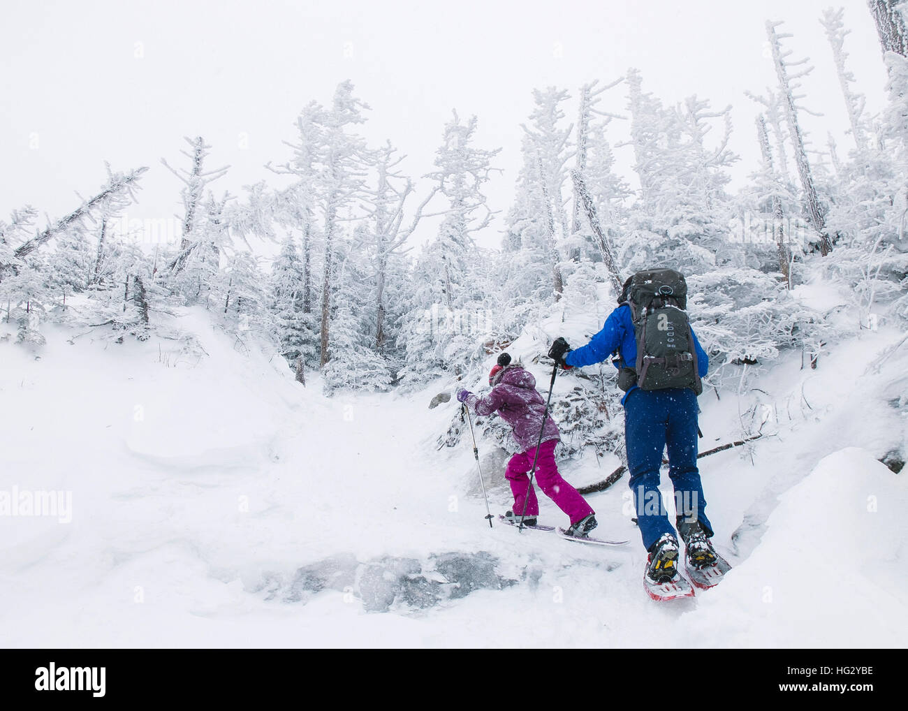 A man and a young girl snowshoe up a snowy mountain in Mont-Megantic, Quebec on Saturday, December 31, 2016. Stock Photo