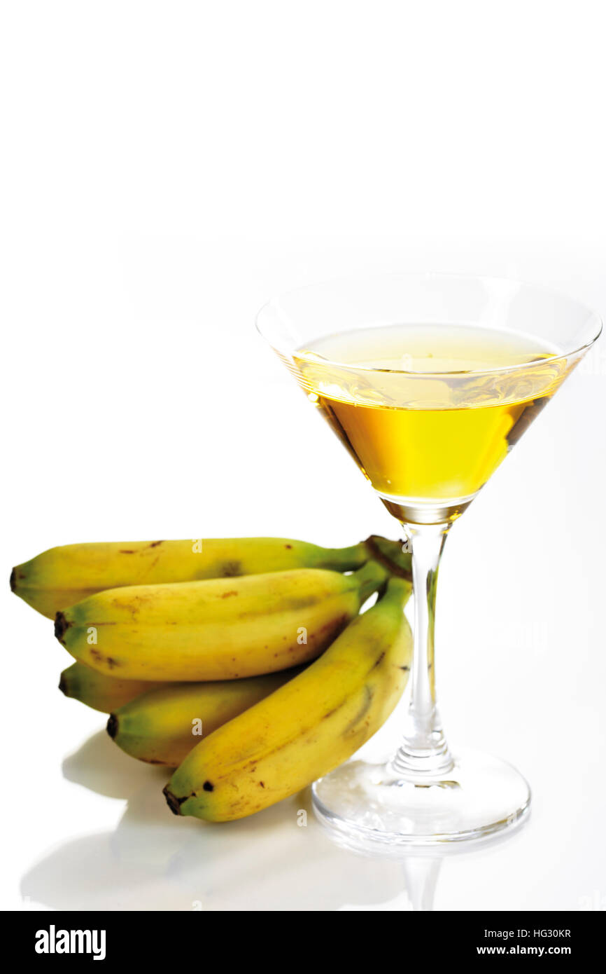Banana liqueur in a cocktail glass with a bunch of miniature bananas