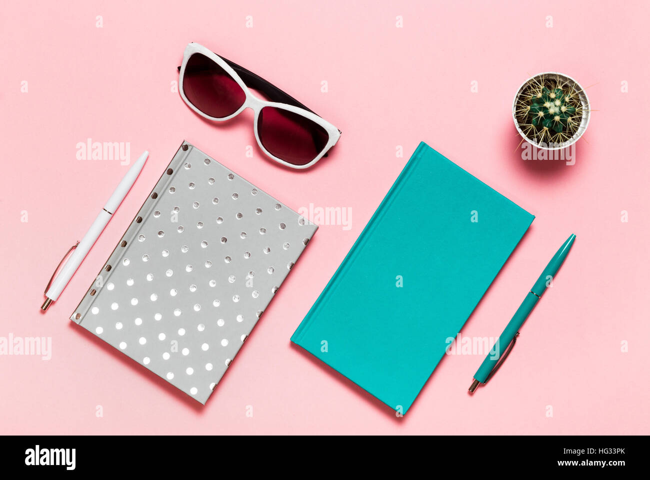 flat lay picture of workspace desk with aquamarine notebook, eyeglasses, cactus copy space pink background, minimal style Stock Photo
