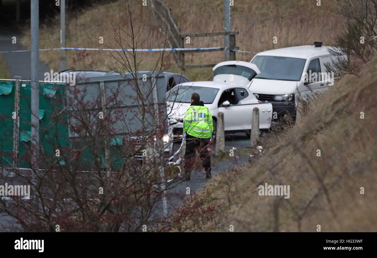 An investigator looks at a silver Audi (obscured by road sign) at the scene near junction J24 of the M62 in Huddersfield where a man died in a police shooting during a 'pre-planned' operation at around 6pm on Monday. Stock Photo